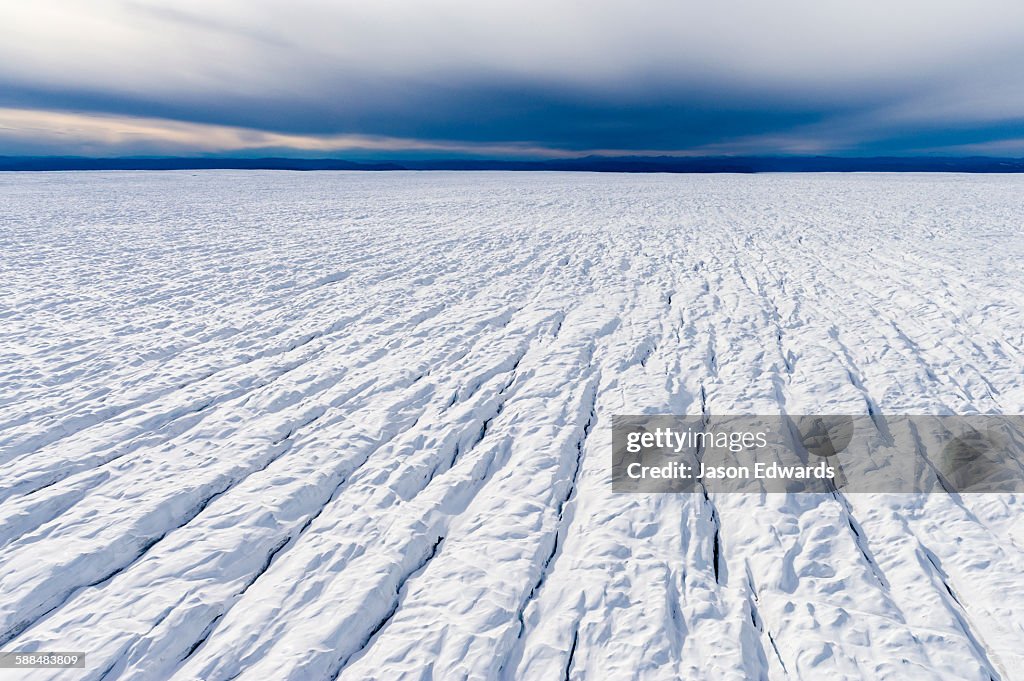 Pressure ridges and crevasse scar the surface of a glacier on the Greenland Ice Sheet.