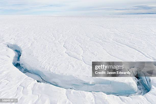 a fracture line dissecting the surface of the ice on the greenland ice sheet. - crevasse fotografías e imágenes de stock