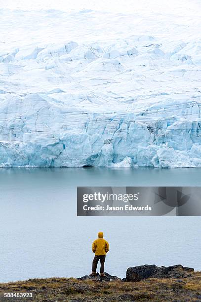 a hiker dwarfed by the fracture zone of a glacier on the greenland ice sheet. - kangerlussuaq stock pictures, royalty-free photos & images