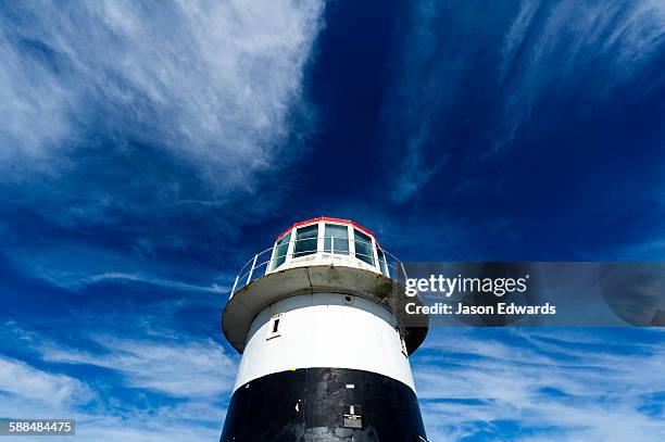 high winds swirl clouds around the pillar of an antique lighthouse. - cape point stock pictures, royalty-free photos & images