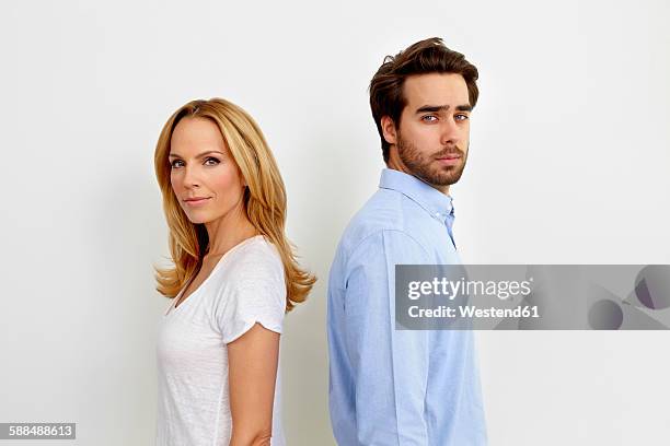 portrait of couple standing back to back in front of white background - 2 jeunes timide fond blanc photos et images de collection