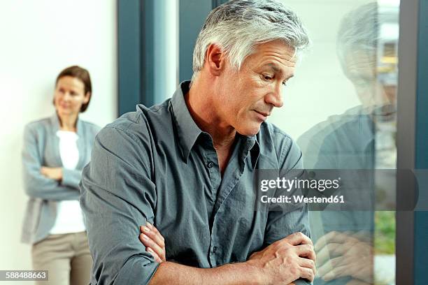 portrait of unhappy man with his his wife standing in the background - married couple fighting stockfoto's en -beelden