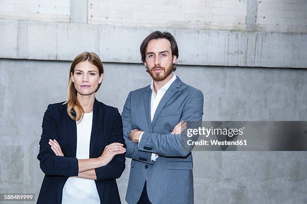 portrait of two business people standing side by side with crossed arms - assertive stockfoto's en -beelden
