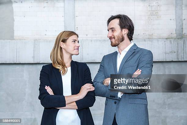 two business people standing face to face with crossed arms - gezicht aan gezicht stockfoto's en -beelden