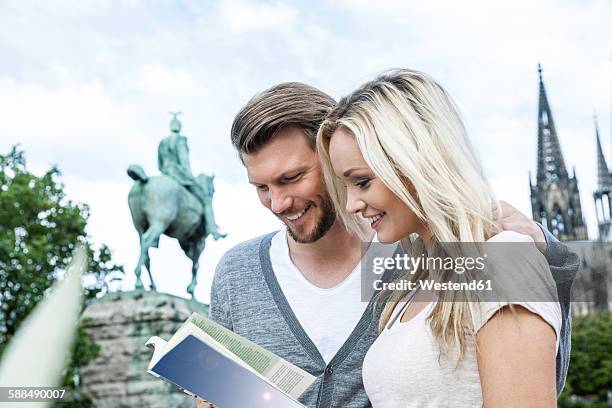 germany, cologne, young couple with guidebook - guidebook stock pictures, royalty-free photos & images