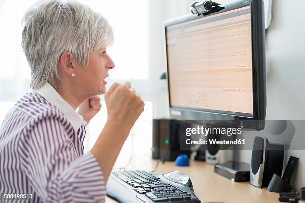 senior woman looking horrified at computer monitor - gesture control screen stockfoto's en -beelden
