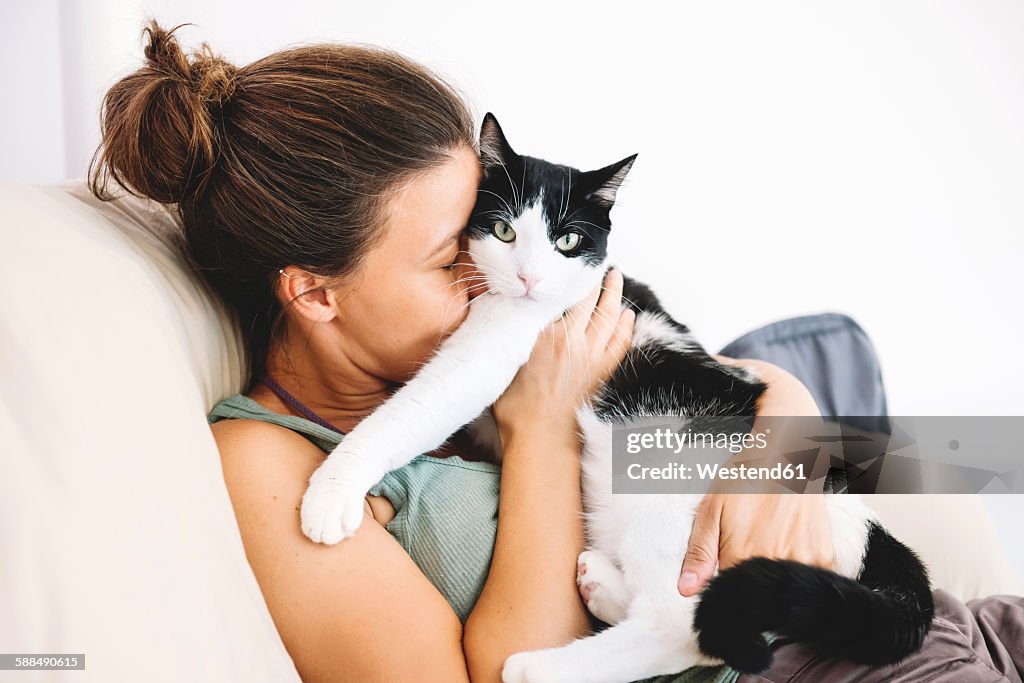 Woman sitting on the sofa hugging her cat