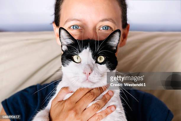 blue eyed woman holding a black and white cat - holding cat imagens e fotografias de stock