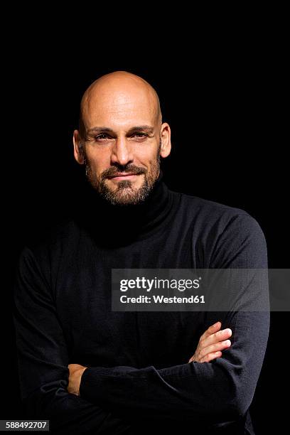 portrait of man with crossed arms wearing black turtleneck in front of black background - high contrast stock pictures, royalty-free photos & images