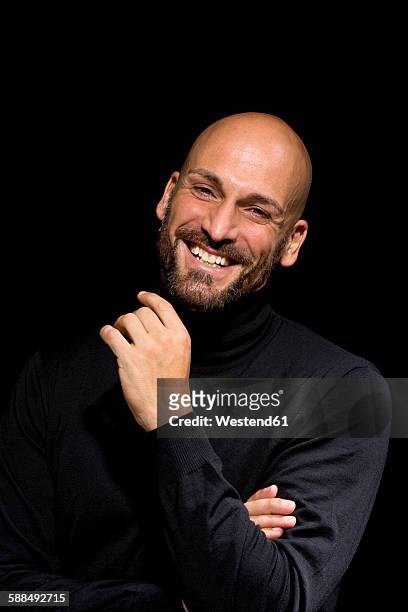 portrait of laughing man wearing black turtleneck in front of black background - alto contraste imagens e fotografias de stock