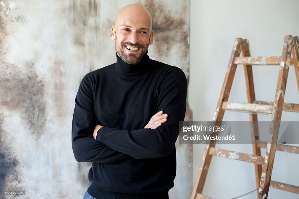 Portrait of smiling man with crossed arms wearing black turtleneck