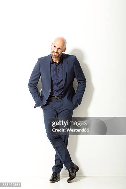 bald man with beard wearing blue suit standing in front of white background - blauw pak stockfoto's en -beelden