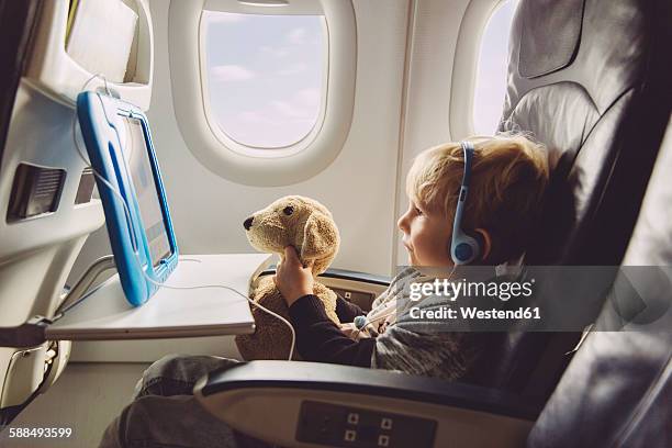 little boy sitting on an airplane watching something on digital tablet - aircraft wifi fotografías e imágenes de stock