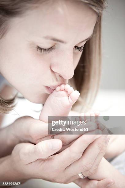 young mother kissing foot of baby girl - foot kiss stock pictures, royalty-free photos & images