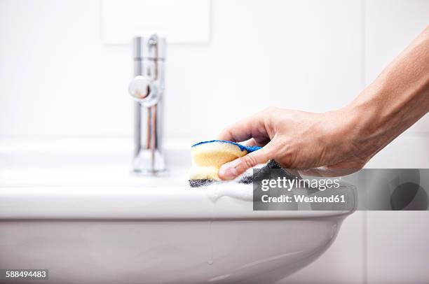 woman cleaning bathroom sink with sponge - bathroom sink stock-fotos und bilder