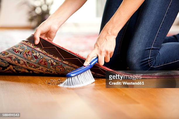 woman sweeping under the carpet - sweeping dirt stock pictures, royalty-free photos & images