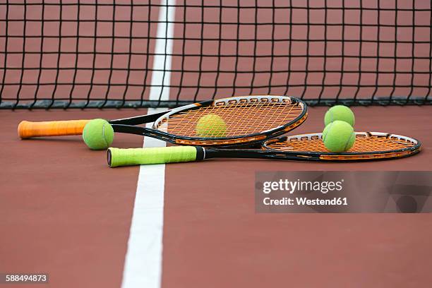 two tennis rackets and four balls lying on ground of tennis court - racquet stock-fotos und bilder