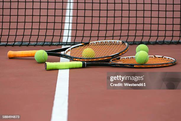 two tennis rackets and four balls lying on ground of tennis court - tennis raquet stock pictures, royalty-free photos & images