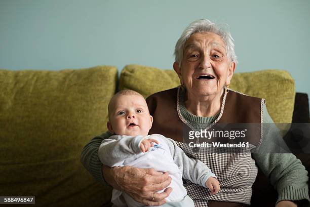 portrait of great-grandmother sitting on a couch with her great-grandson - great grandmother stock pictures, royalty-free photos & images