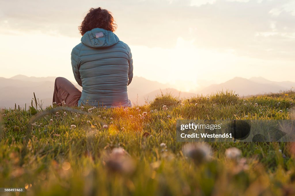 Austria, Tyrol, Unterberghorn, hiker resting in alpine landscape at sunrise