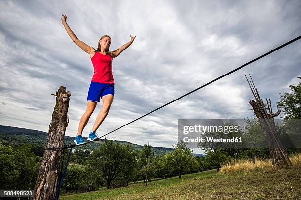 young woman balancing on slackline - slackline foto e immagini stock