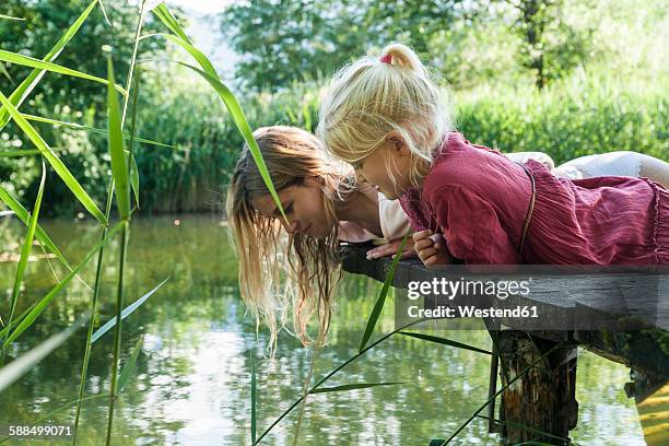 mother and daughter lying on jetty at a lake looking at water - children nature photos et images de collection