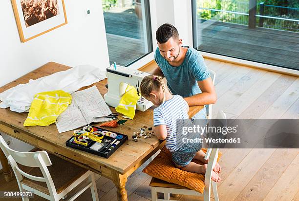 father and daughter at home using sewing machine - näherin stock-fotos und bilder