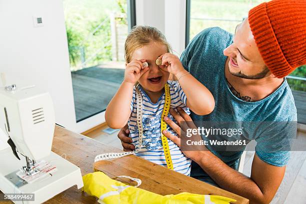 playful father and daughter at home with sewing machine - button craft stock pictures, royalty-free photos & images