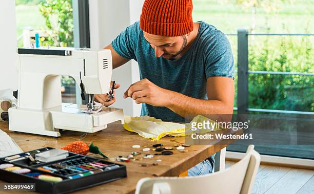 young man at home using sewing machine - sewing machine imagens e fotografias de stock