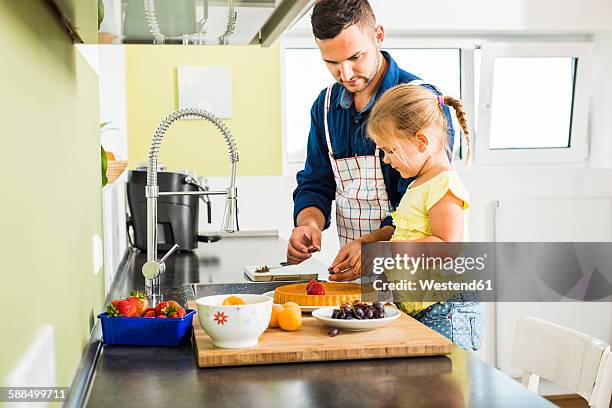 father and daughter in kitchen preparing fruit cake - fruitcake stock-fotos und bilder