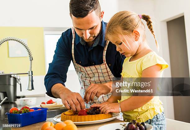 father and daughter in kitchen preparing fruit cake - fruitcake stock-fotos und bilder