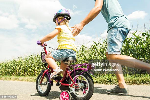 father accompanying daughter on bike - training wheels stock pictures, royalty-free photos & images