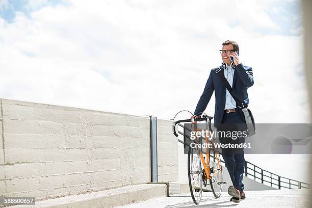 businessman pushing bike while talking on the phone - man on cell phone walking in the city stock pictures, royalty-free photos & images