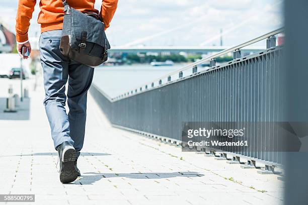 businessman with shoulder bag walking, rear view - legs walking stock-fotos und bilder