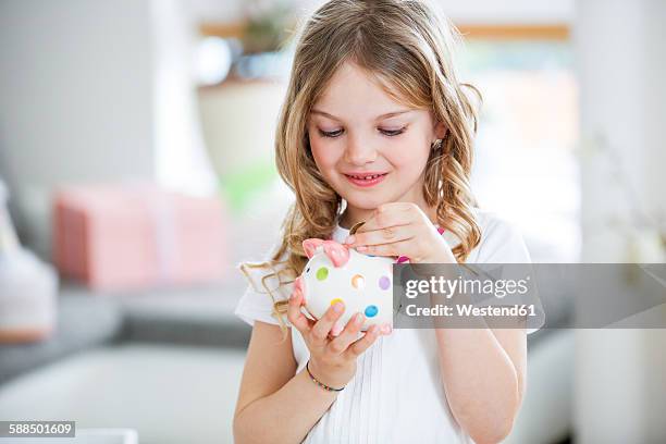 girl throwing coin into piggy bank - pocket money stock pictures, royalty-free photos & images