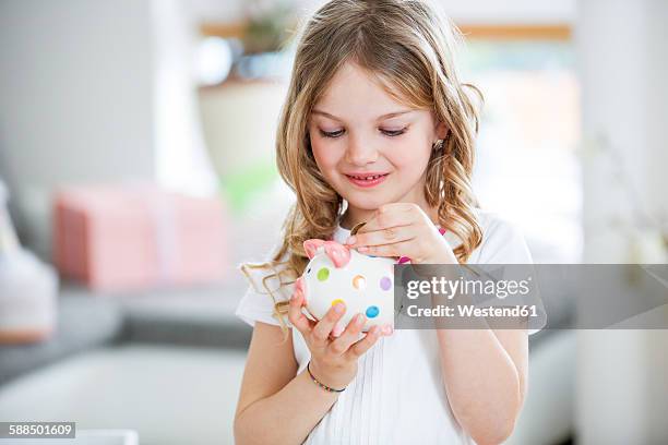 girl throwing coin into piggy bank - allowance stock pictures, royalty-free photos & images