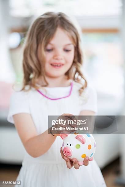 girl throwing coin into piggy bank - allowance stock-fotos und bilder