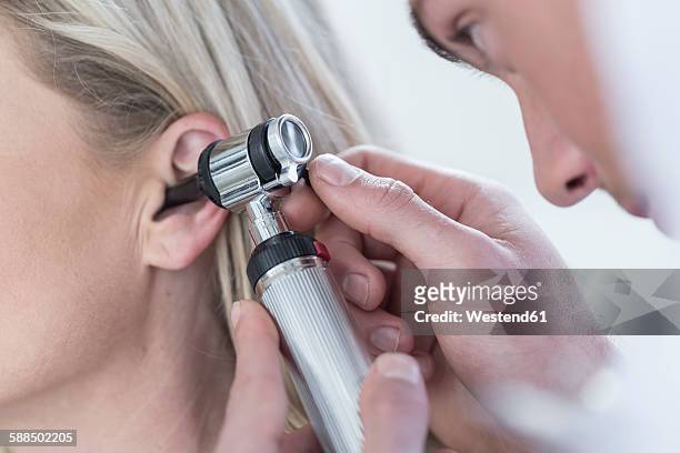 doctor examining patient with otoscope - ear stockfoto's en -beelden