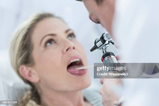 doctor examining patient's throat - human tongue foto e immagini stock
