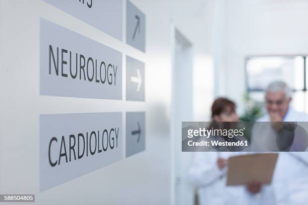 direction signs on hospital wall with doctors in background - hospital sign stock pictures, royalty-free photos & images