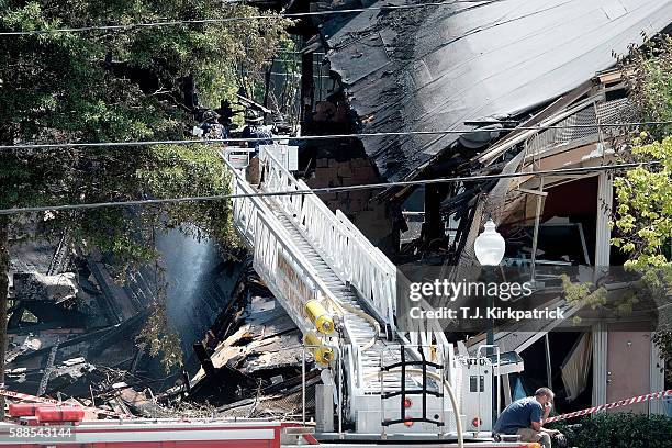 Firefighters on a ladder truck from Montgomery County Fire and Rescue spray water on the still-smouldering remains of a structure after an overnight...