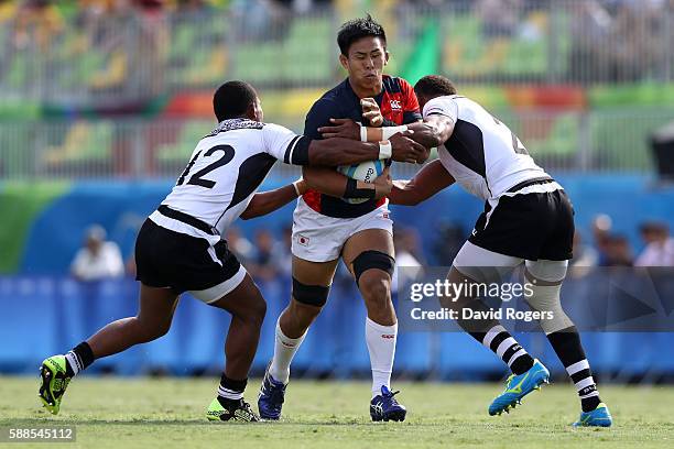 Yoshitaka Tokunaga of Japan is tackled by Vatemo Ravouvou and Jasa Veremalua of Fiji during the Men's Rugby Sevens semi final match between Fiji and...