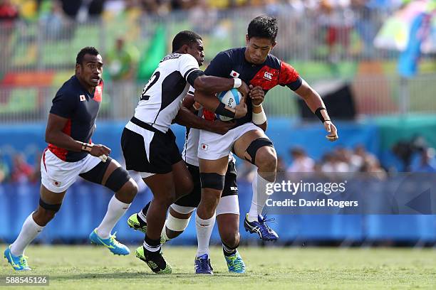 Yoshitaka Tokunaga of Japan is tackled by Vatemo Ravouvou and Jasa Veremalua of Fiji during the Men's Rugby Sevens semi final match between Fiji and...