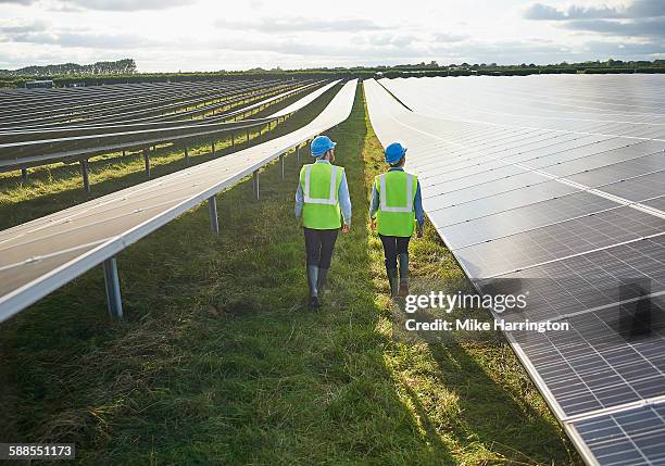 surveying engineers in safety wear in solar farm - umweltverantwortung stock-fotos und bilder