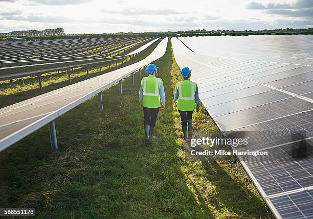 surveying engineers in safety wear in solar farm - environmental stewardship stock pictures, royalty-free photos & images