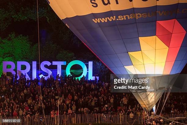 Members of the public watch tethered hot air balloons perform a 'nightglow' on the opening day of the Bristol International Balloon Fiesta on August...