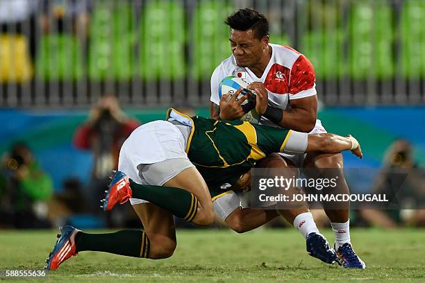 Japan's Lomano Lemeki is tackled by South Africa's Juan de Jongh in the mens rugby sevens bronze medal match between Japan and South Africa during...