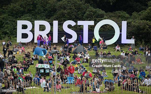 Members of the public gather to watch as balloonists set up a tethered hot air balloons to perform in the 'nightglow' on the opening day of the...