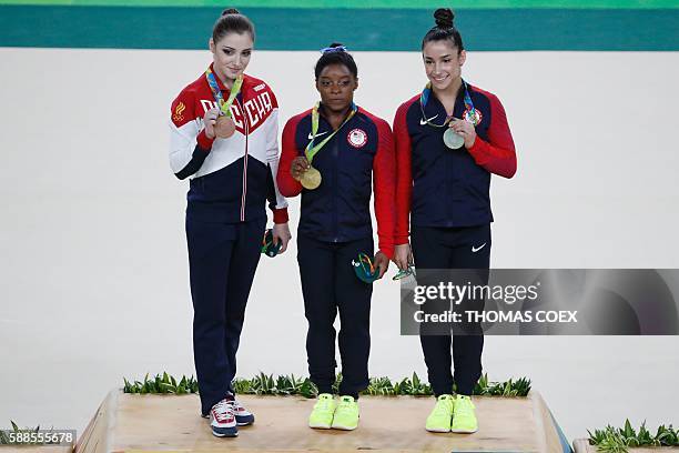 Russia's Aliya Mustafina, US gymnast Simone Biles and US gymnast Alexandra Raisman celebrate on the podium of the women's individual all-around final...