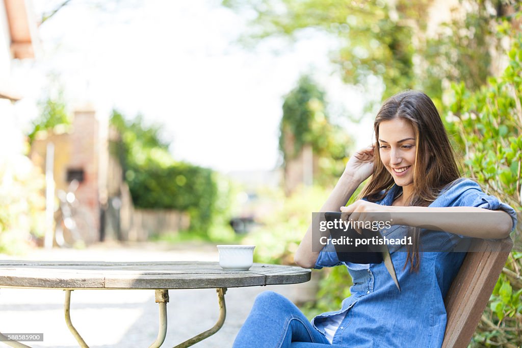 Jeune femme assise à l’extérieur et lisant un livre électronique